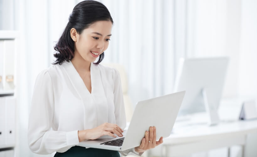 charming ethnic businesswoman using laptop