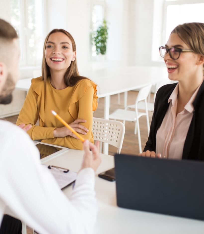 two beautiful business women happily talking with male applicant work young smiling employers spending job interview modern office